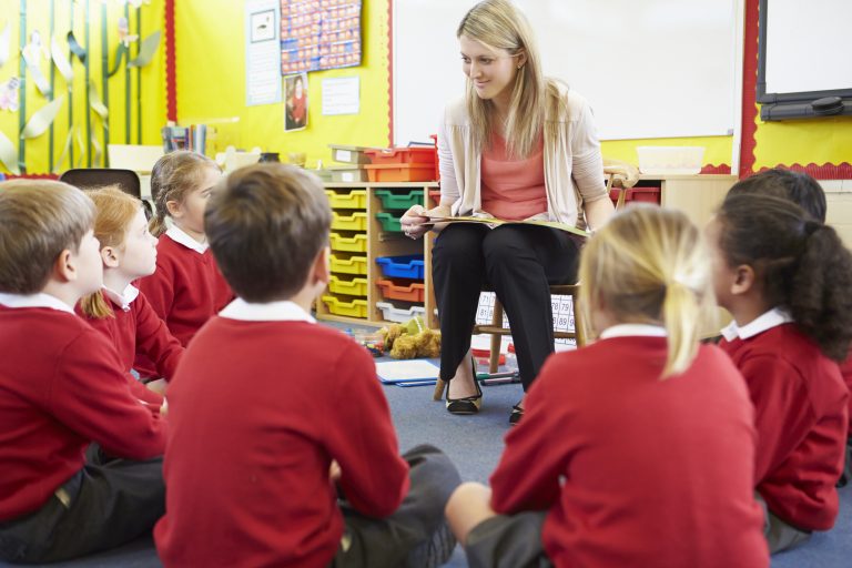Primary school children sitting around a teacher