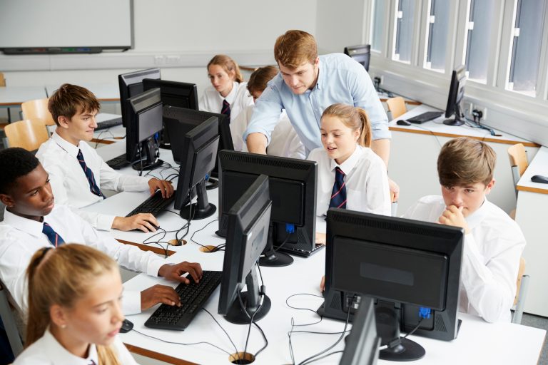 Teacher in school helping student review work on the computer