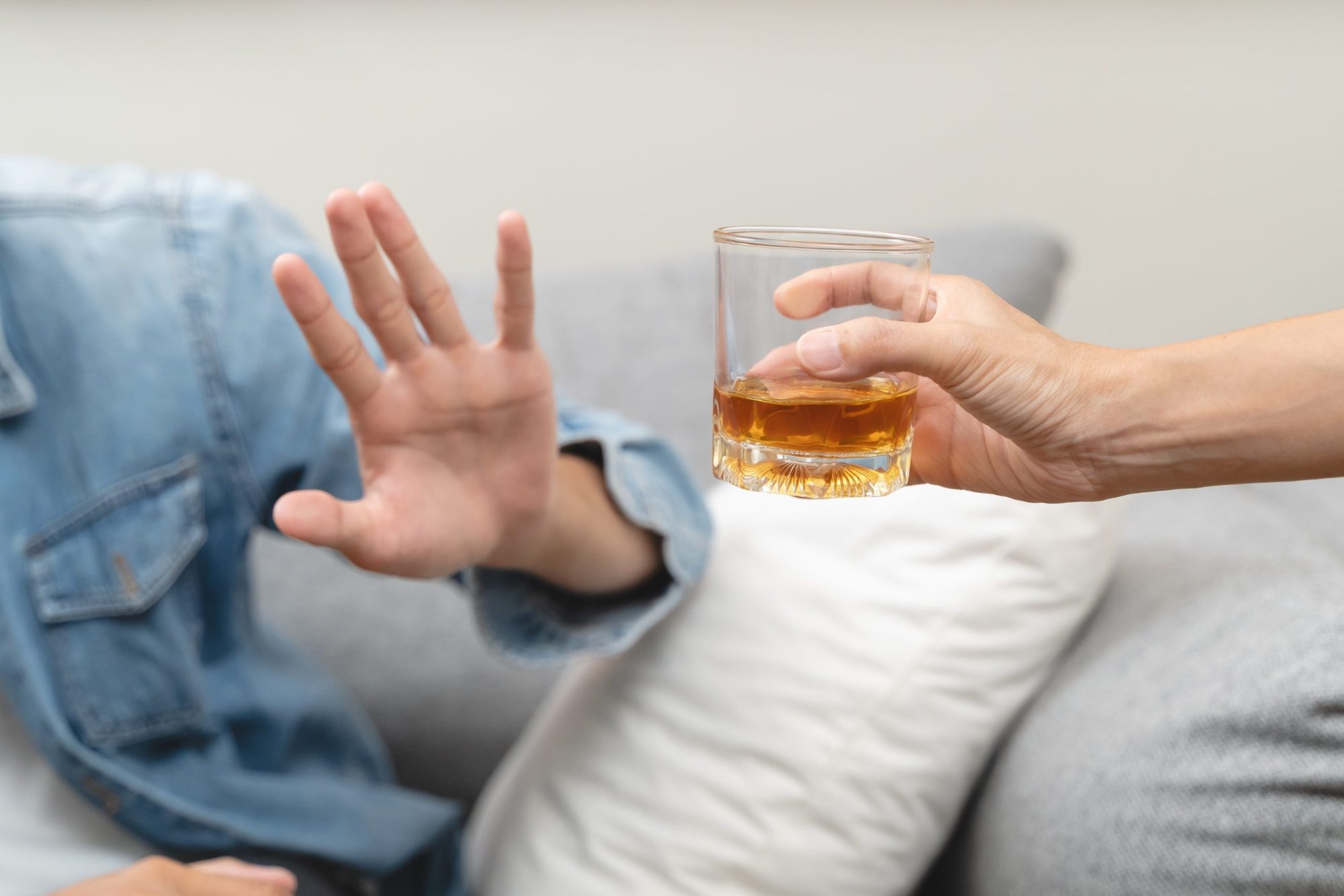 A hand refusing a drink of alcohol