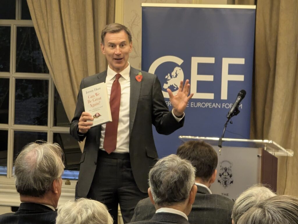 WhatsApp Image 2025-11-11 at 18.43.43 Jeremy Hunt speaking to the Conservative European Forum reception, holding up a copy of his book in front of a CEF banner, talking about global leadership and China