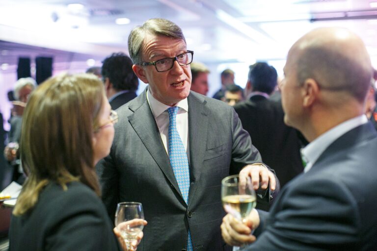 Peter Mandelson speaking to two people who are facing away from the camera.