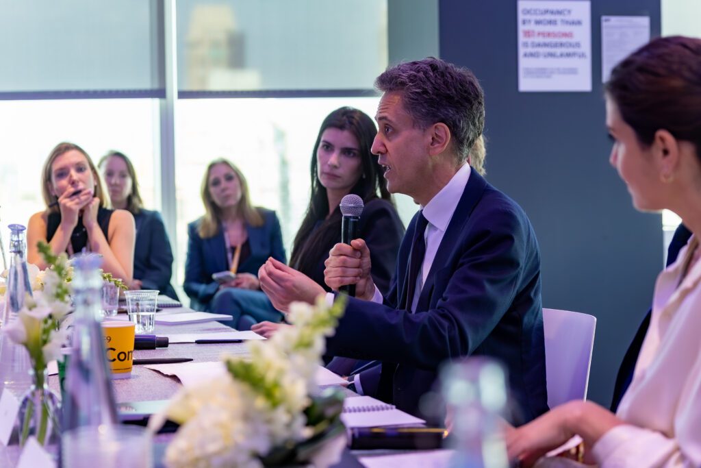 Ed Miliband speaking at a conference, with a microphone in hand.