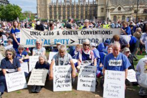 Palestine Action protestors holding signs showing their support for the organisation.